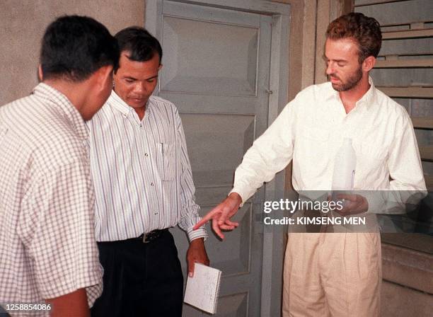 Philip Williams from Dunbart in Scotland, talks with plain-clothes Cambodian police at the Municipal Court, in Phnom Penh, 24 May after being charged...