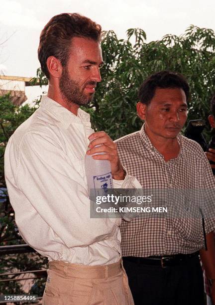 Philip Williams from Dunbart in Scotland, talks with plain-clothes Cambodian police at the Municipal Court, in Phnom Penh, 24 May after being charged...