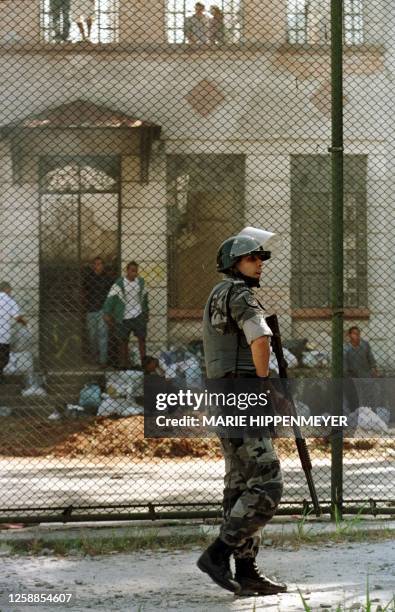 Brazilian riot policeman stands outside the juvenile detention center known as "Febem," as rebellious inmates stands outside one of the institution's...