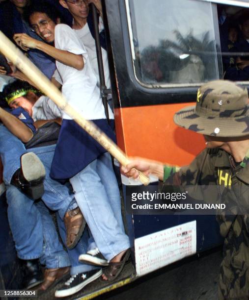 An Indonesian soldiers beats students with a stick as they try to escape on a bus 31 March 1999 during clashes between students and security forces...