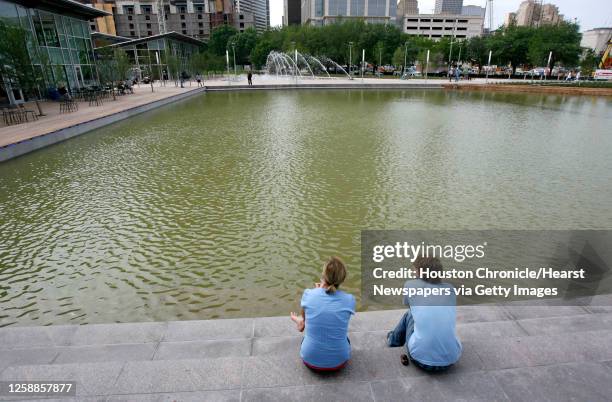 Mary Stengel, left, and Ben Taft, assistants for the artist Margo Sawyer sit beside the Kinder Lake at Discovery Green, the new downtown park, as...