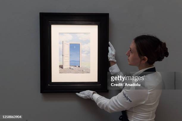 Staff member holds a painting titled âLe Savoirâ by Rene Magritte during a photocall at Sotheby's auction house showcasing the highlights of Summer...
