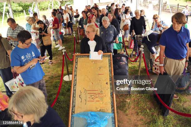 Sturbridge, MA A woman waits in a tent with a large framed piece of art at Sturbridge Village for an episode of the Antiques Roadshow TV show.