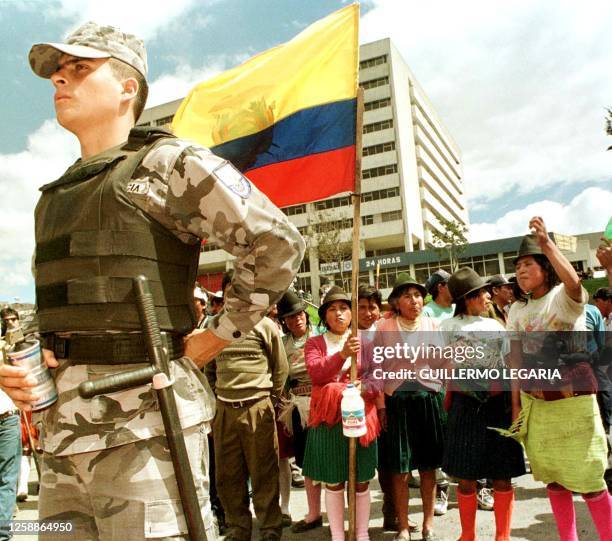 An Ecuadoran anti-riot police officer stands guard in front of protesters demanding the resignation of President Jamil Mahuad in Quito 20 January,...