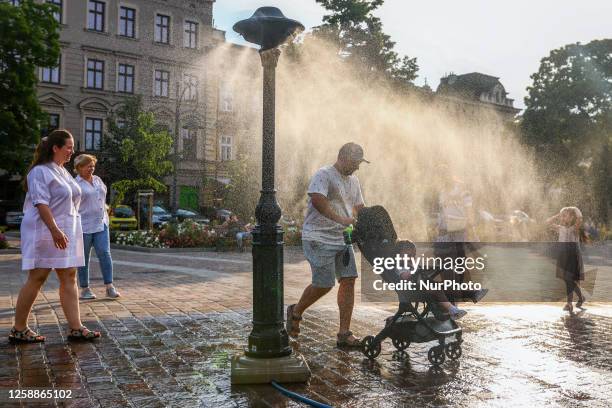 People are cooling by a water sprinkler at the Podgorski Square in Krakow, Poland on June 20, 2023. Hot air masses covered the country and...