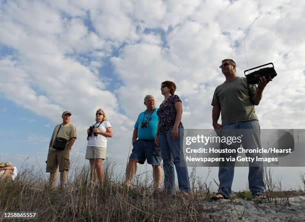 Brad Lott holds a radio as he and others listen to the delay for the space shuttle on the beach at Jetty Park near Cape Canaveral,Thursday, Feb. 24...