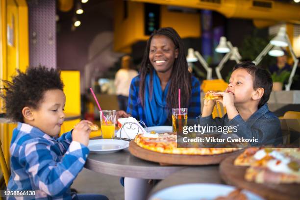 mother and children eating pizza - kid eating restaurant stock pictures, royalty-free photos & images