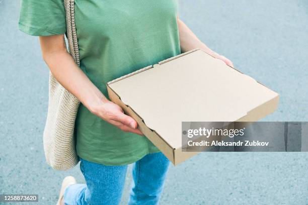 a stylish fashionable woman or girl is holding a cardboard box or a package of hot italian pizza. home delivery, fast food. - i was turning into a vegetable stock pictures, royalty-free photos & images