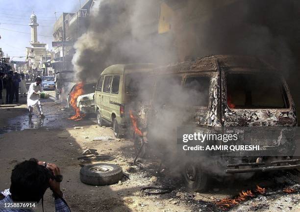 Flames and smoke spew out of burning cars, set ablaze by an angry mob after the killing five Sunni Muslim clerics by unidentified gunmen earlier in...