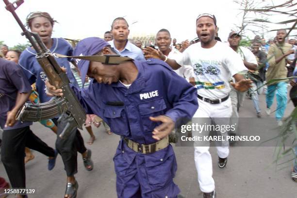 Democratic Republic of Congo policeman tries to control the crowd as the body of slain President Laurent Kabila arrives at the People's Palace in...