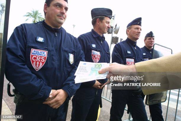 Demonstrator from the Alliance for French Sovereignty group hands a 100 Euro bank note to a police officer in the streets of Nice as the EU summit...