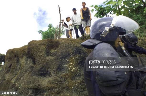 Anti-riot Police watch, 28 September 2000, after evacuating several families who occupied lands in a district of Managua, Nicaragua. The settlers...