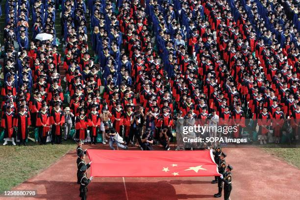 Students from Wuhan University watching the flag raising ceremony during the graduation ceremony in the school's stadium in Wuhan. According to local...