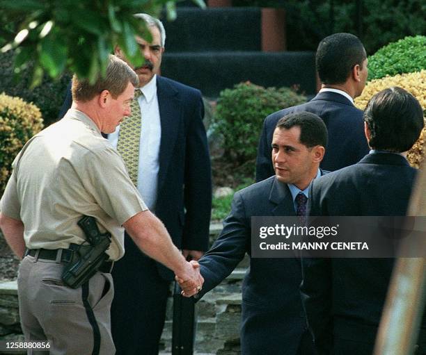 Juan Miguel Gonzalez , Elian Gonzalez's father, shakes hands with an unidentified Montgomery County, MD police officer who is providing security in...