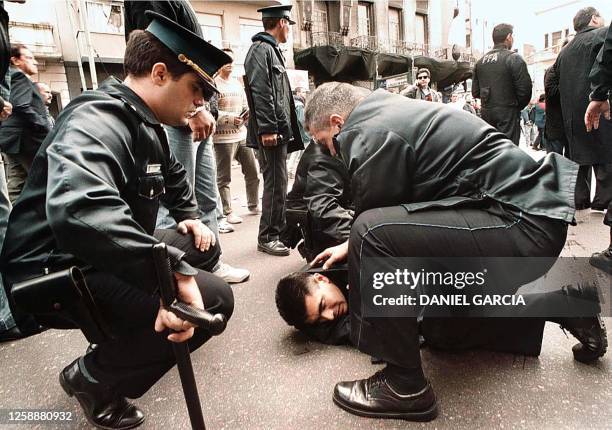 Argentine police attend to a man during a confrontation with workers, 19 April 2000, near the National Congress in Buenos Aires, Argentina. Policias...