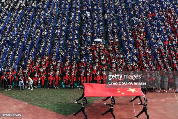 Students from Wuhan University watching the flag raising ceremony during the graduation ceremony in the school's stadium in Wuhan. According to local...