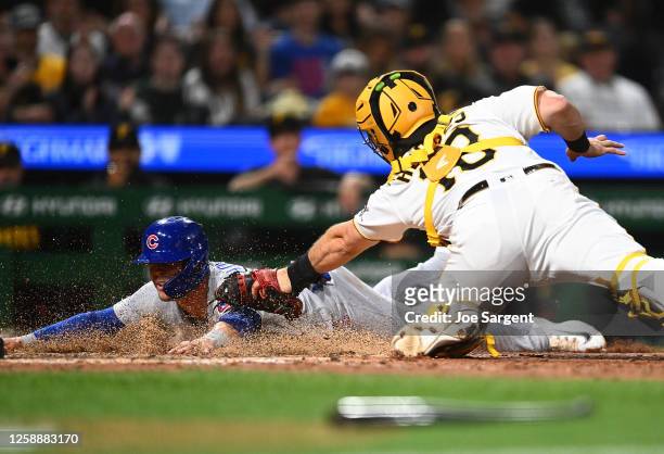 Nico Hoerner of the Chicago Cubs slides safely into home plate in front of Austin Hedges of the Pittsburgh Pirates during the eighth inning at PNC...