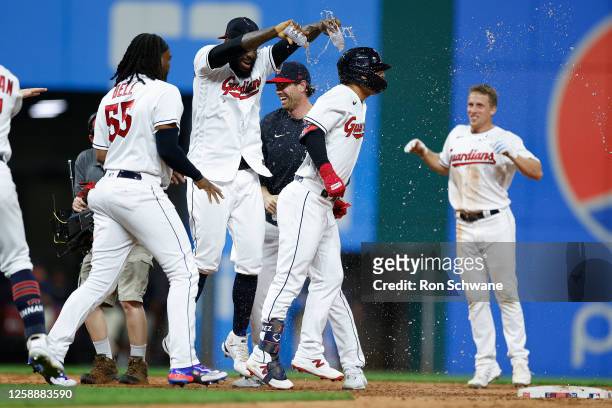 Andres Gimenez of the Cleveland Guardians gets mobbed by teammates after getting the game-winning single off Trevor May of the Oakland Athletics...