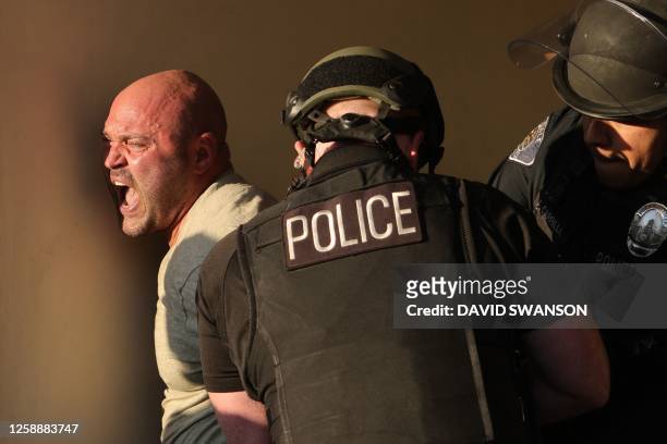 Police detain a demonstrator as they gather outside the Glendale Unified School District headquarters in Glendale, California, on June 20, 2023. Over...