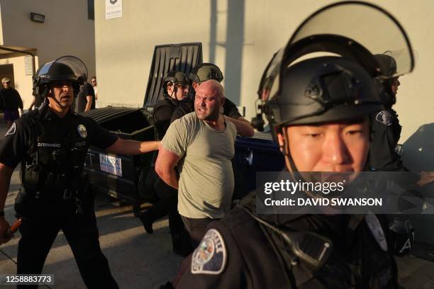 Police detain a demonstrator as they gather outside the Glendale Unified School District headquarters in Glendale, California, on June 20, 2023. Over...