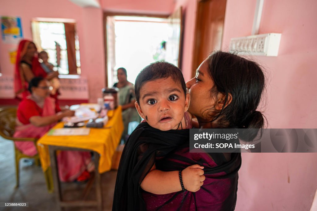 A mother carrying her young child waits for vaccination at...
