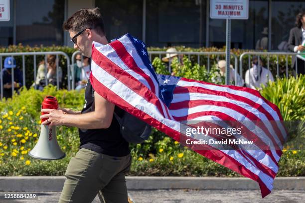 An anti-LGBTQ+ demonstrator wears an American flag outside a Glendale Unified School District Board of Education meeting on June 20, 2023 in...