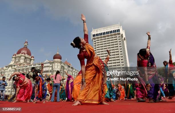 People are performing Yoga on the day of International Yoga Day near the iconic monuments Gateway Of India and Taj Palace Hotel in Mumbai, India, on...