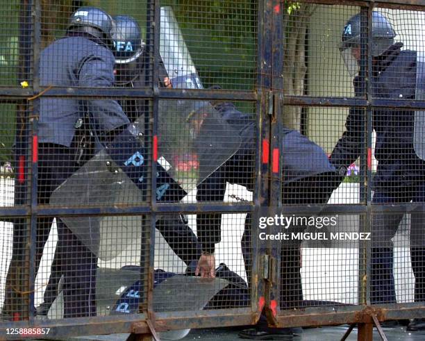 Argentine Federal Police take cover as employees of the Spanish-owned Aerolines Argentinas throw eggs and tomatoes 26 July 2001, at the company's...