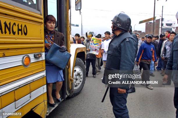 Passenger gets off a bus which was stopped by a blockade of protesting transportation workers as a policeman looks on 14 August 2001 in Lima. A...