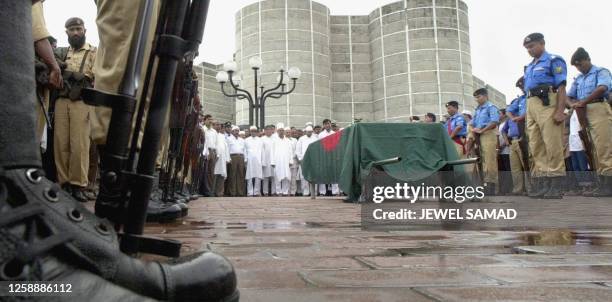 Police put their guns down while they offer guard of honour to the coffin, covered with the national flag, of the parliament speaker Humayun Rashid...