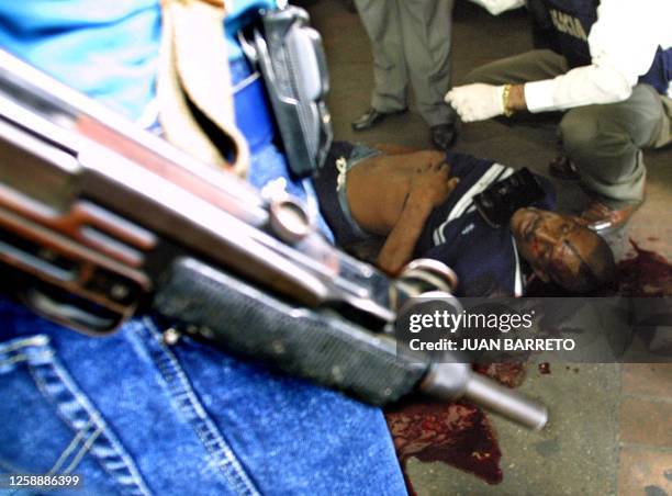 Members of Policia Tecnica Judicial inspect the cadaver of a criminal in downtown Carcas 07 June 2001. Homicides in Venezuela have increased from...