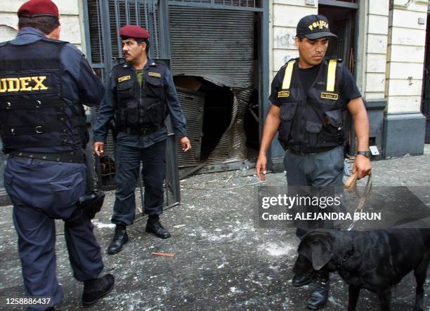 Members of the police Unit of the Explosives Decontamination inspect damage caused by an attack in central Lima, near the National Jury of...