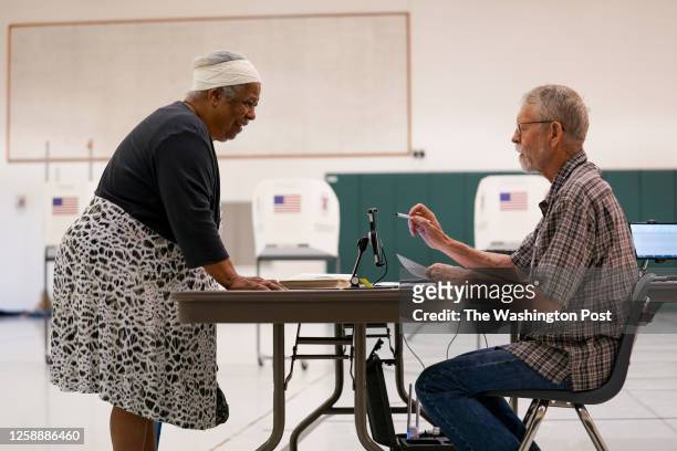 Helen Bryant prepares to vote with the help of election officer David Graham at Rolling Ridge Elementary School as Virginia holds primary elections...