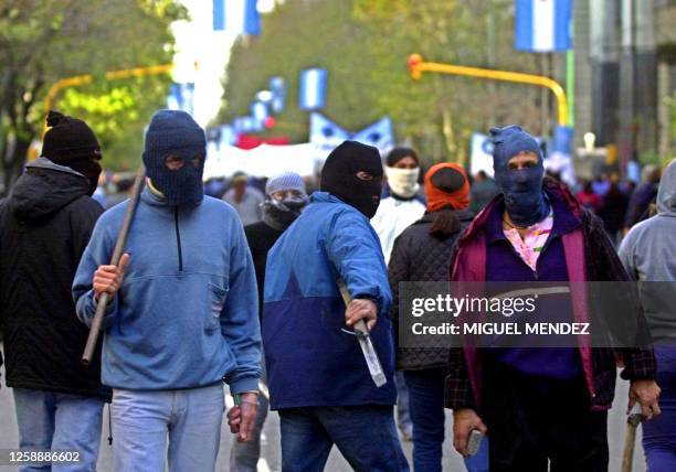 Group of demonstrators with their faces covered, carrying sticks and stones, protest through the Av. De Mayo in Buenos Aires, Argentina, 18 June...