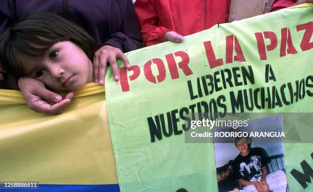 Girl accompanies her mother, 13 May 2001, during a public ceremony in Bogota, Colombia, where mothers and family members of police officers and...