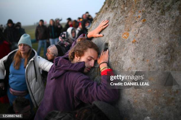 Revellers touch the stones as they celebrate the Summer Solstice at sunrise at Stonehenge, near Amesbury, in Wiltshire, southern England on June 21...