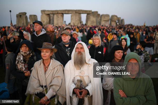 Revellers stand by the stones as they watch the sunrise at Stonehenge, near Amesbury, in Wiltshire, southern England on June 21 to celebrate the...