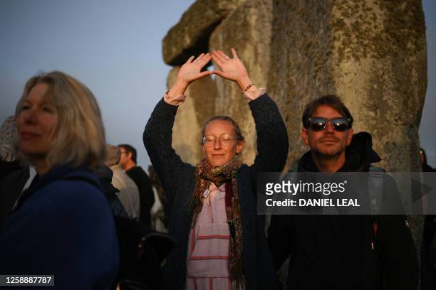 Revellers celebrate the Summer Solstice as the sun rises at Stonehenge, near Amesbury, in Wiltshire, southern England on June 21 in a festival, which...