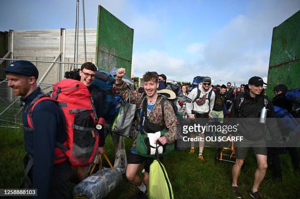 Festivalgoers pass through the main gate as they arrive to attend the Glastonbury festival in the village of Pilton, in Somerset, southwest England,...