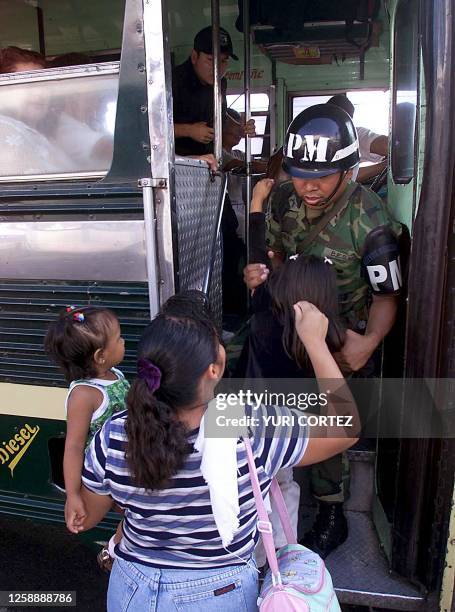 Military police officer is seen helping a women and children on board the governemnet mandated bus in San Salvador, El Salvador 28 November 2001. Un...