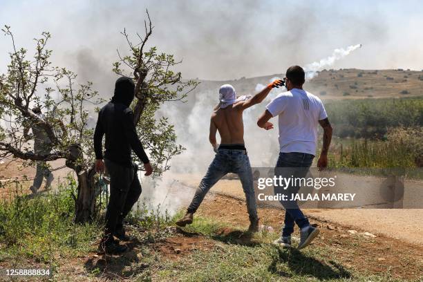 Members of the Druze community throw back a tear gas canister as they protest against an Israeli wind turbine project reportedly planned in...