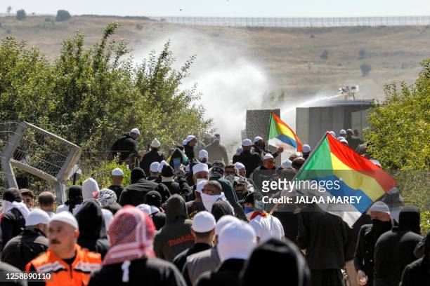 Tear gas fumes fill the air as members of the Druze community gather with their flags in a protest against an Israeli wind turbine project reportedly...