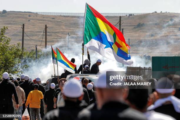 Tear gas fumes fill the air as members of the Druze community gather with their flags in a protest against an Israeli wind turbine project reportedly...