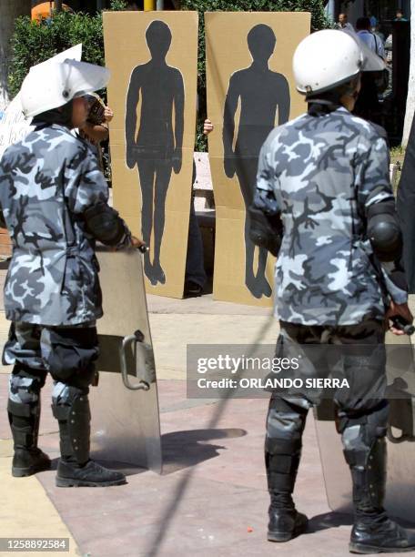 Anti-riot police secure the area in Tegucigalpa, Honduras as relatives of missing family members lift cardboard silhouettes in protest 25 January...