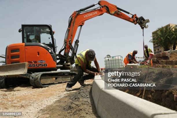 Employees work on a sidewalk construction under 39 degres Celcius during a heat wave the French Mediterranean island of Corsica, in Ajaccio on June...