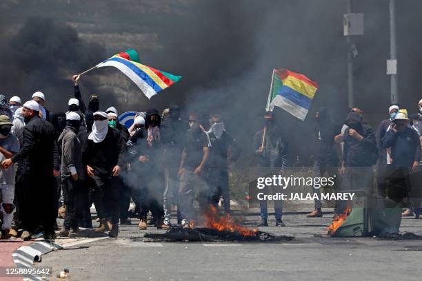 Members of the Druze community wave flags during a protest in their village of Masada in the Israel-annexed Golan Heights on June 21 against an...