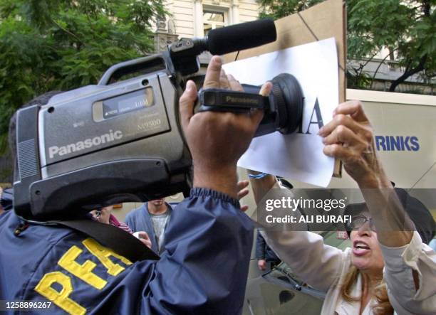 Protester covers the Argentinian Police camera lense in front of the banco Boston in the financial zone of Buenos Aires, Argentina, 27 May 2002....