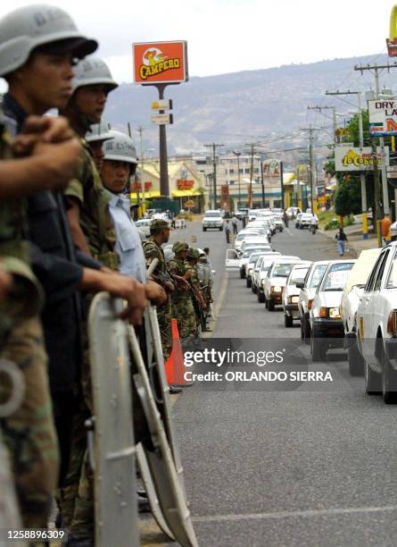 Hoduran soldiers and agents from the National Guard look on while a caravan of at least three thousand taxi-drivers protest in Tegucigalpa for the...