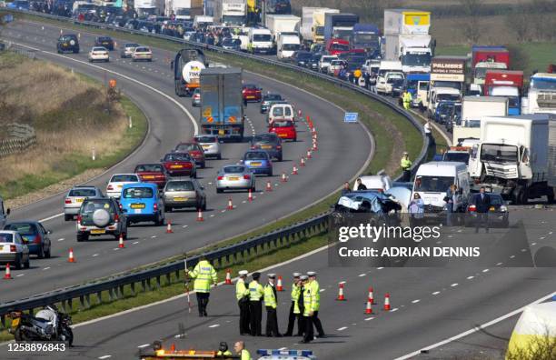 Police and rescuers are seen 28 March 2002 at the site of a multiple car crash on the eastbound section of the M40 motorway near Thame, Oxfordshire,...