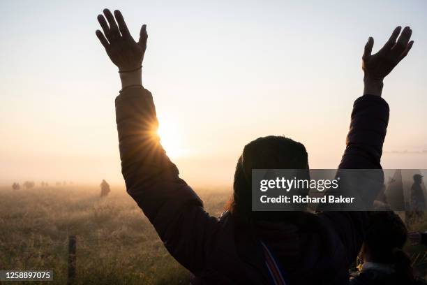 Spiritually-minded revellers celebrate sunrise during the summer Solstice at the ancient late-Neolithic stones of Stonehenge, on 21st June 2023, in...